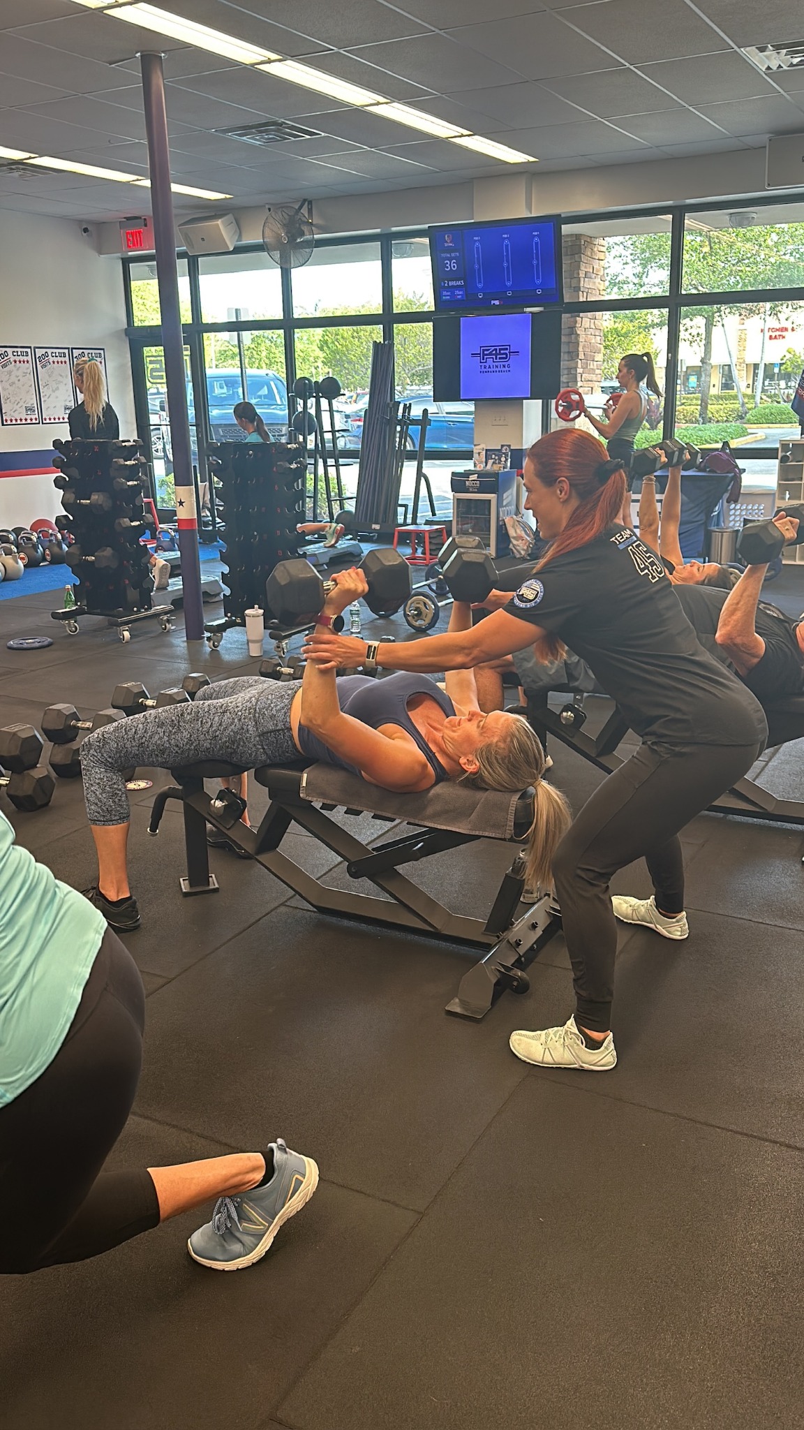 F45 coach helping a member during a strength workout